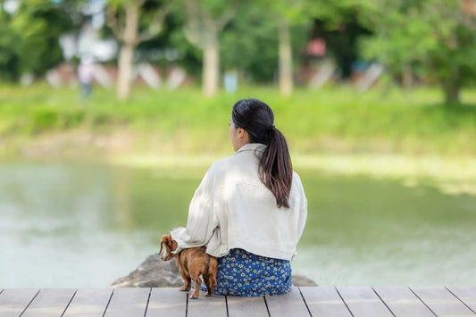 Woman sitting quietly with her dog by a lake