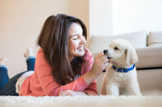 Woman smiling and interacting with a puppy on a yoga mat during a Mother’s Day puppy yoga class